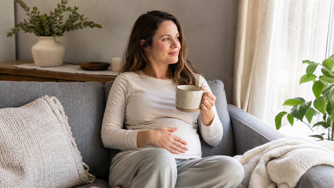 Woman sitting upright on a sofa with herbal tea while recovering from abdominal surgery